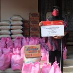 Penyandang disabilitas netra sedang memegang paket bantuan.