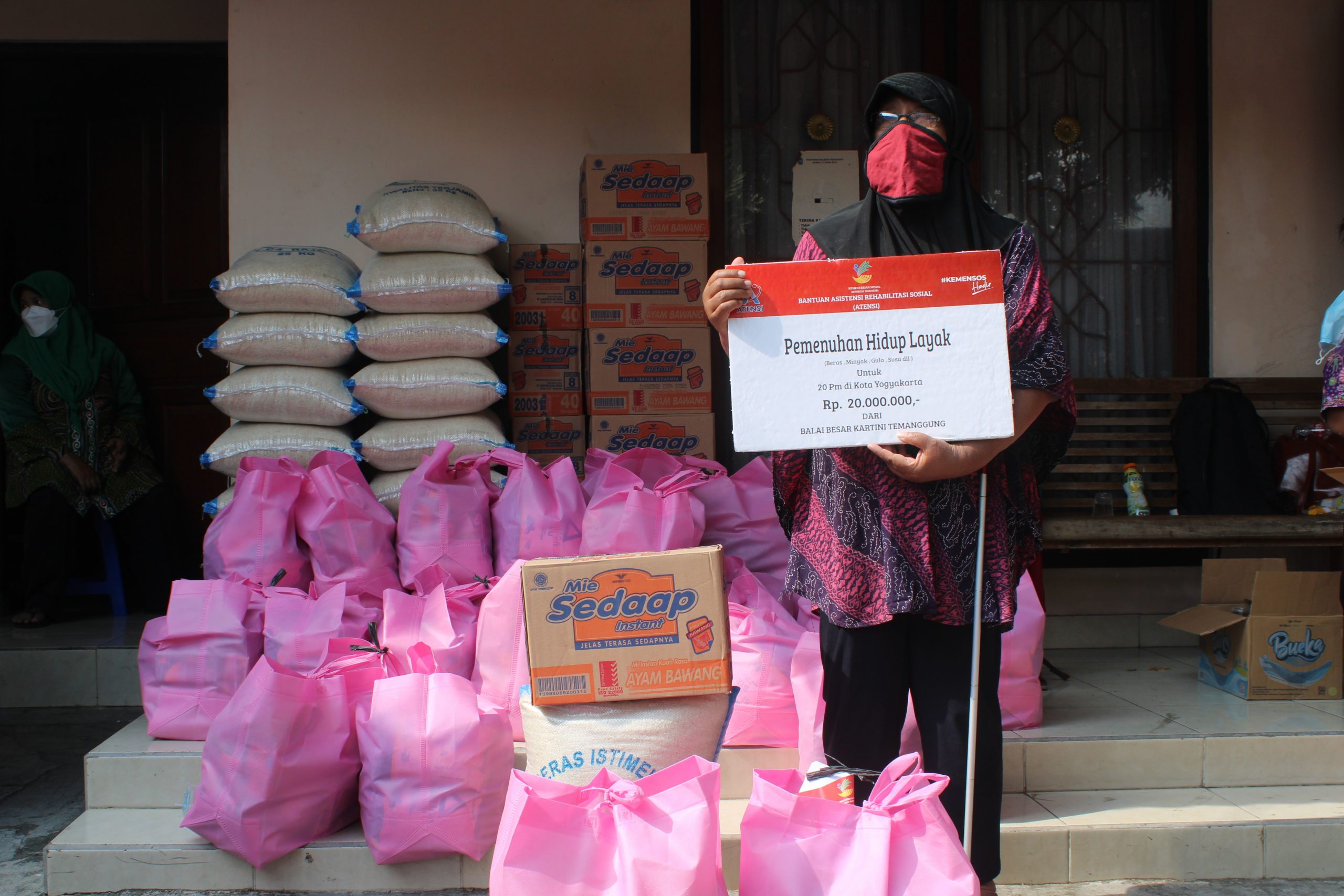 Penyandang disabilitas netra sedang memegang paket bantuan.