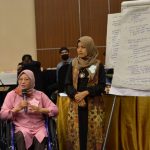 Peserta penyandang disabilitas pengguna kursi roda sedang mempresentasikan rencana pendampingan kasus.