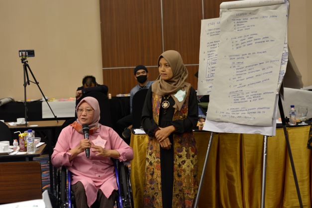 Peserta penyandang disabilitas pengguna kursi roda sedang mempresentasikan rencana pendampingan kasus.